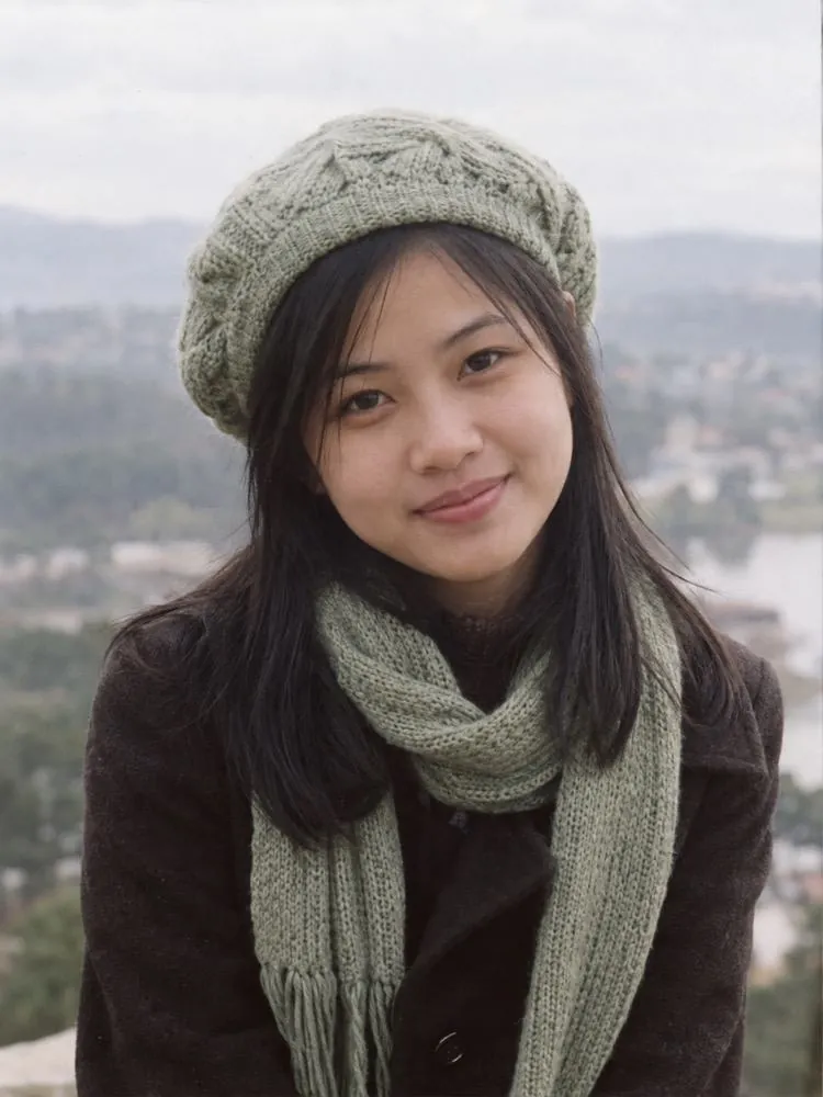 Ảnh chân dung Nguyễn Mai Diệp: cô gái đội mũ len, quàng khăn, phía sau là đồi thông Đà Lạt.